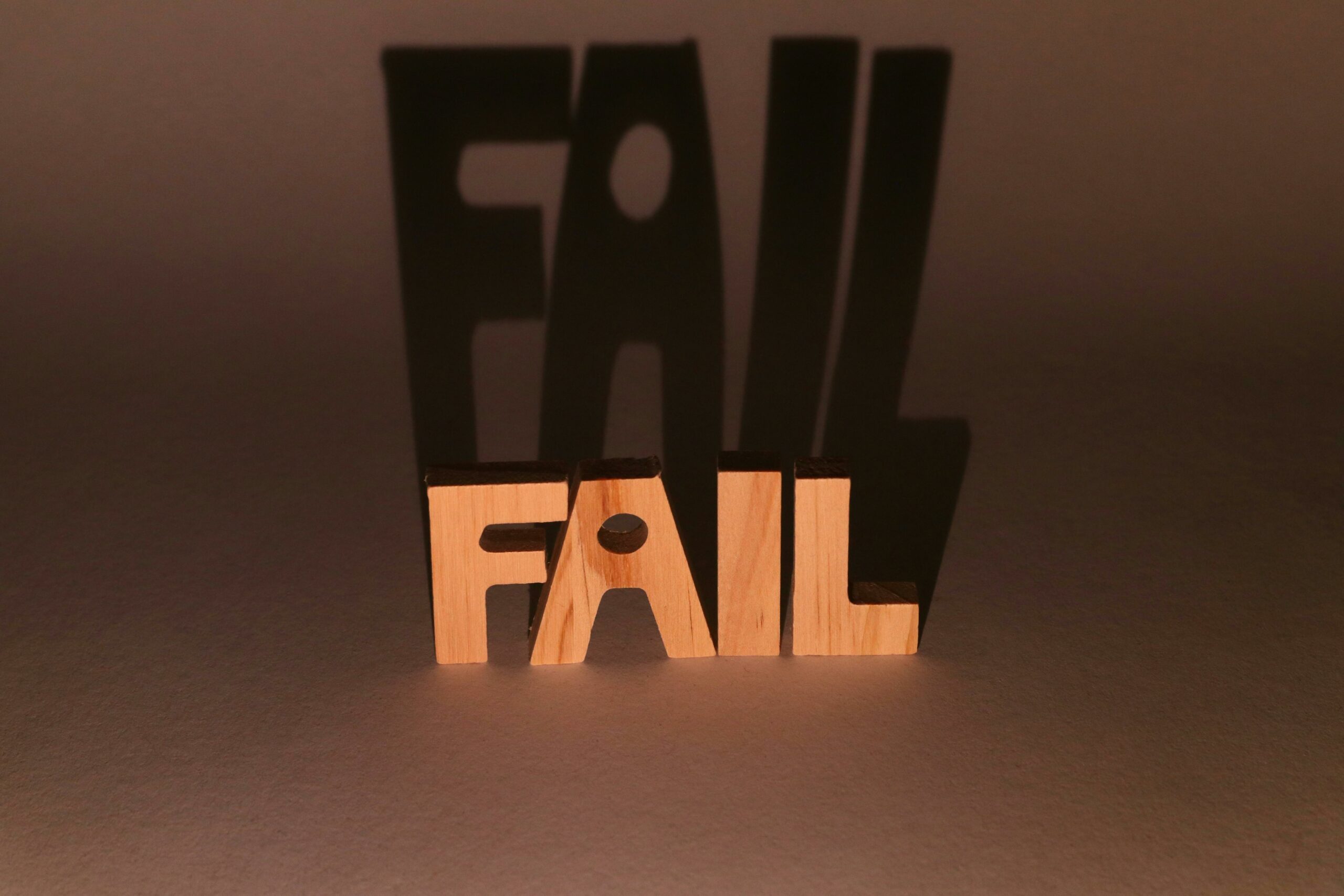 Wooden letters spelling "FAIL" with an elongated shadow.